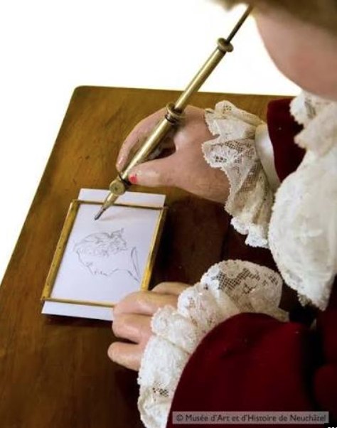 Close-up of the automaton's hand guiding the quill over the paper